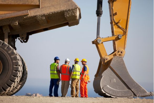 a construction crew standing next to a large excavator