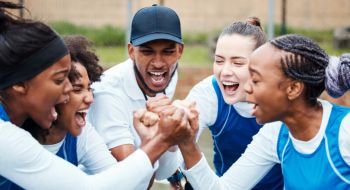 team members put their hands in and cheer before a game